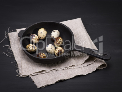 quail eggs in the shell lie in a black cast-iron frying pan
