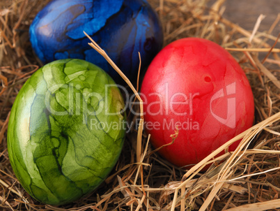 Three colored Easter eggs in a nest