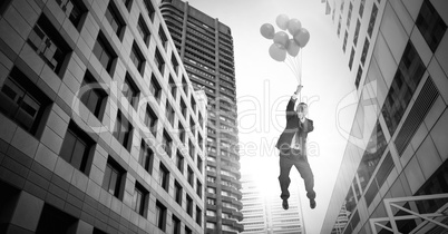 Businessman floating with balloons over surreal city buildings perspective