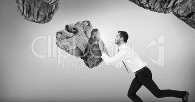 Businessman pushing surreal rocks suspended in the air