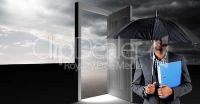 Man holding umbrella and surreal open door with grey cloudy sky