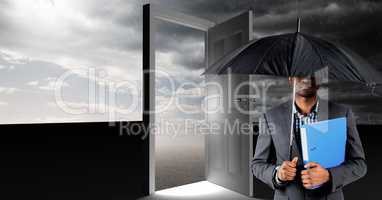 Man holding umbrella and surreal open door with grey cloudy sky