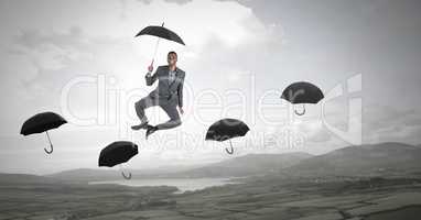 Man holding umbrella jumping across umbrella's over nature landscape