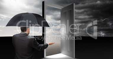 Man holding umbrella and open door with surreal grey cloudy sky