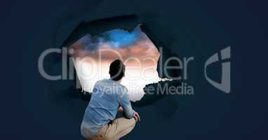 Man looking through surreal paper hole at sky