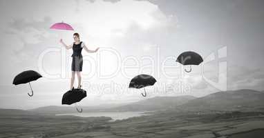 Woman holding umbrella walking across umbrella's over nature landscape