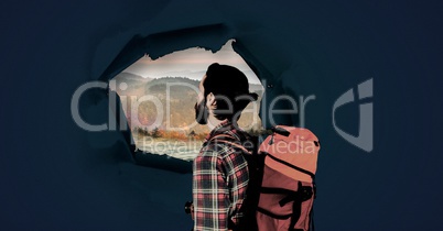 Hiking adventurer man looking through surreal paper hole at nature landscape