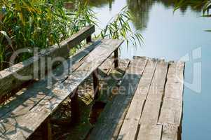 old Park bench by the water, broken wooden bench in the forest for tourists