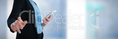 Composite image of mid section of businesswoman using mobile phone while using imaginary interface