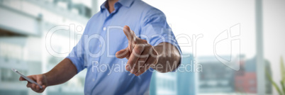 Composite image of male executive pressing an invisible virtual screen while using mobile phone