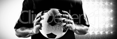 Composite image of mid section of football player in black jersey holding ball