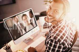 Composite image of portrait of man smiling while sitting by computer