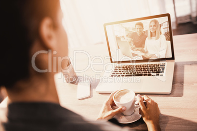 Composite image of businesspeople working over laptop at desk in creative office