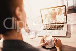 Composite image of businesspeople working over laptop at desk in creative office