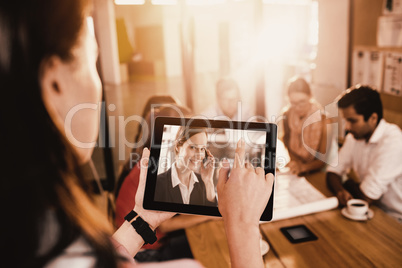 Composite image of businesswoman using digital tablet while discussing with colleagues