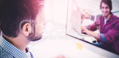 Composite image of graphic designer using laptop at his desk