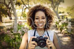 Portrait of smiling woman standing with digital camera