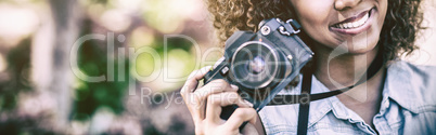 Smiling woman with digital camera at park