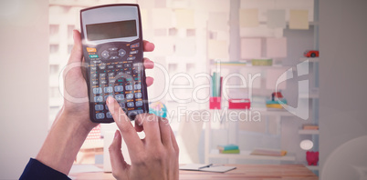 Composite image of hands of businesswoman using calculator