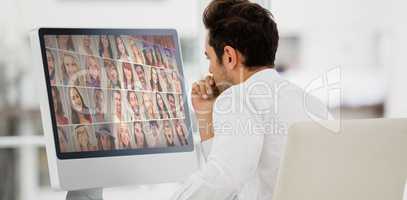 Composite image of rear view of businessman looking at computer monitor