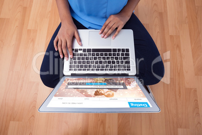 Composite image of mid section of female executive using laptop while sitting on wooden floor