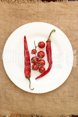 tomatoes and pods of chili peppers on the plate. Vegetables on the sacking