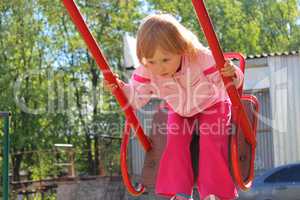 Little girl plays on the swing. Childhood the better years