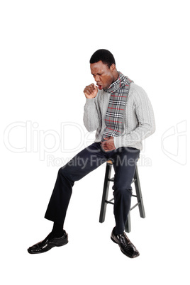Coughing young African man sitting on chair