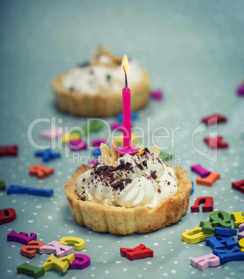 cake with white cream and a pink burning candle