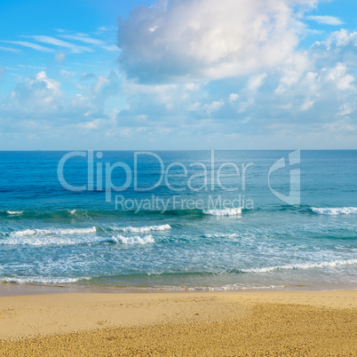 Deserted sandy beach of the Indian Ocean. In the blue sky cumulu