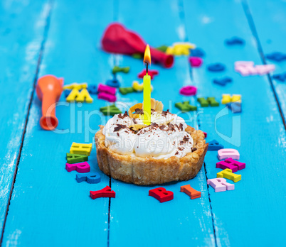 sweet cake with white cream and a burning yellow candle