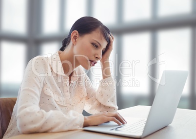 Businesswoman working on laptop by bright fresh windows