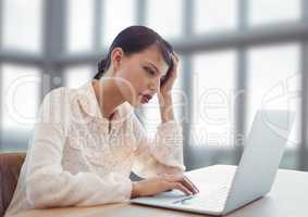 Businesswoman working on laptop by bright fresh windows