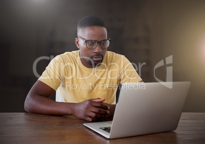 Businessman working on laptop with yellow flare in city