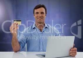 Businessman working on laptop with bank card and purple background