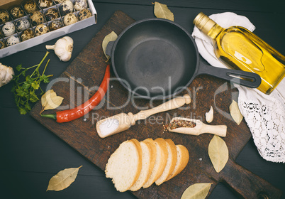 raw quail eggs and an empty round black cast-iron frying pan