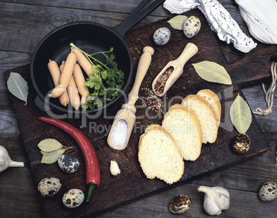 small meat sausages with a frying pan and raw quail eggs