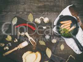 sausages in a black round cast-iron frying pan and raw quail egg