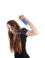 Woman putting hair spray on her hair