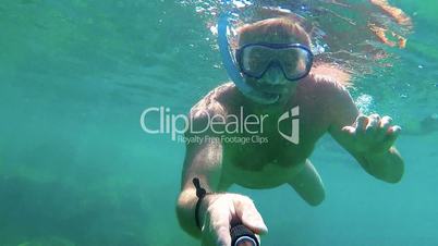 Young man in the clear ocean water driving with snorkel