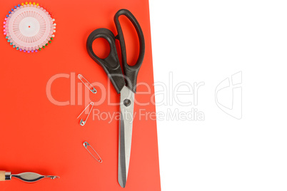 Tailoring scissors and pins on a red background. Free space for