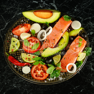 Fillet of red fish and spices on black background.