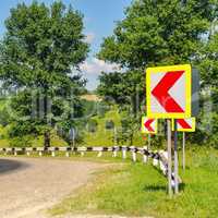 A winding road with steep turns in the hilly terrain. Green fiel