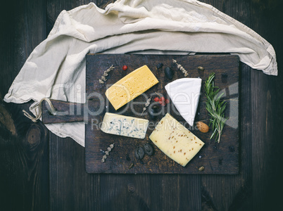 pieces of different cheeses on a brown wooden board