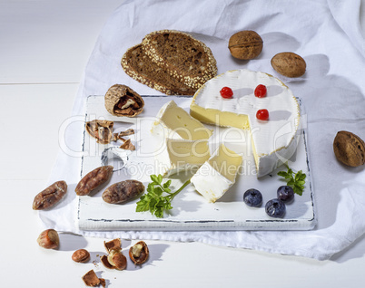 round Camembert cheese on a white wooden board