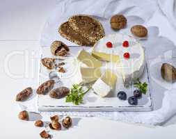 round Camembert cheese on a white wooden board