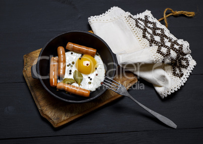 fried eggs and sausages in a black frying pan