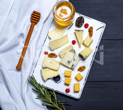 pieces of cheese on a white board and a glass jar with honey