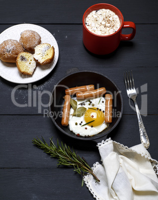 egg with sausages in a black frying pan, cocoa with marshmallows