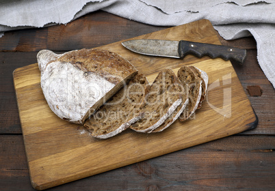 sliced bread with rye flour flour on a brown wooden board